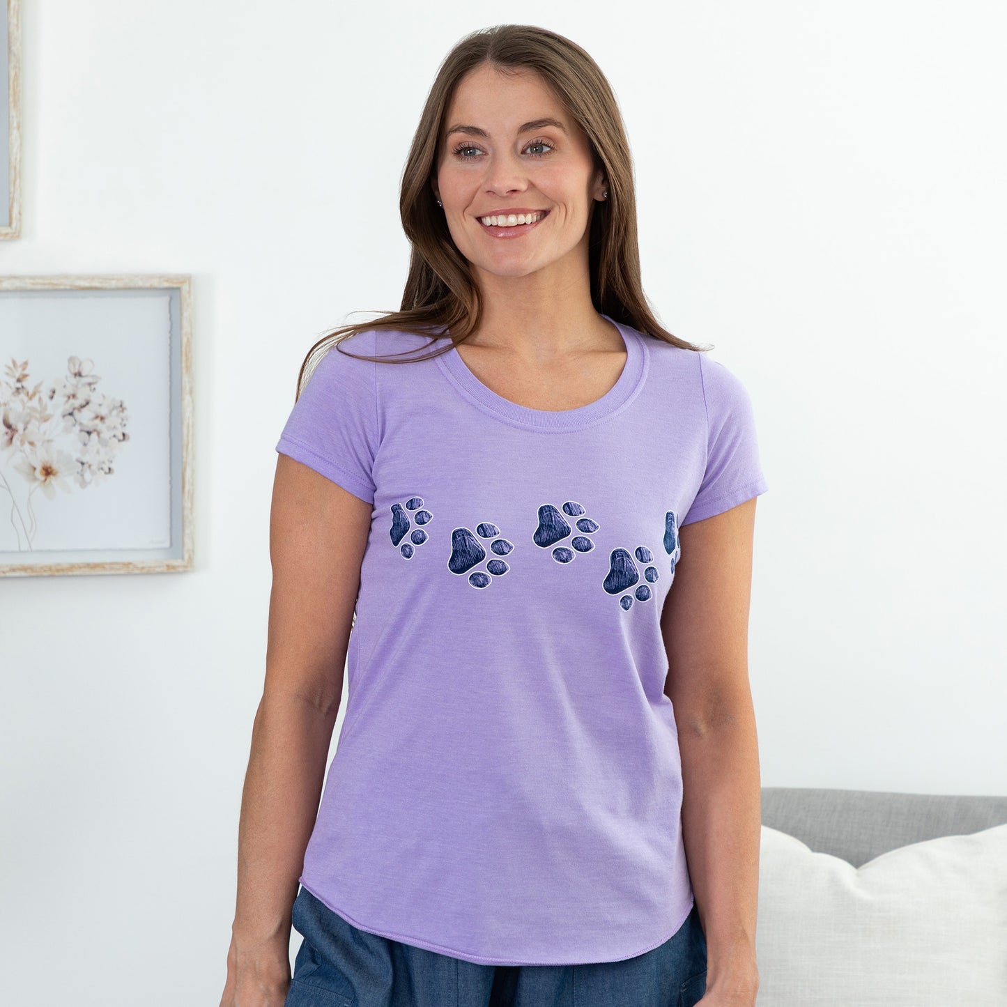 Woman wearing a purple t-shirt with paw prints in a room.