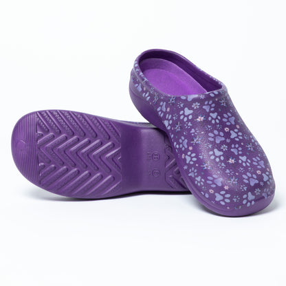 Purple clogs with floral paw print pattern, with a textured sole, on a white background