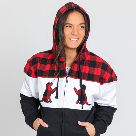 A woman wearing a plaid zip hoodie with dog silhouette details on the front, with a white background.