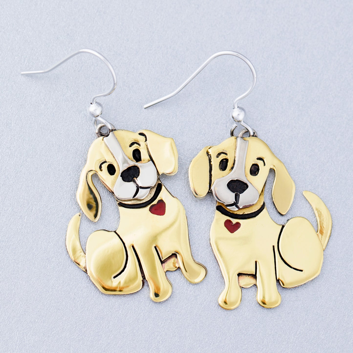 Brass dog-shaped earrings on a light gray background