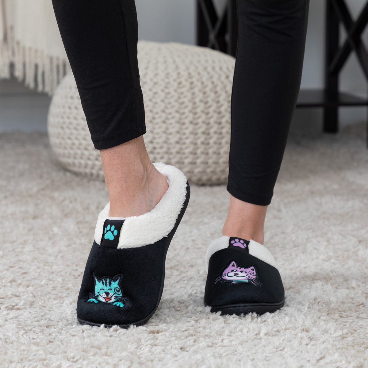 Model wearing purple and teal cat slippers and black leggings