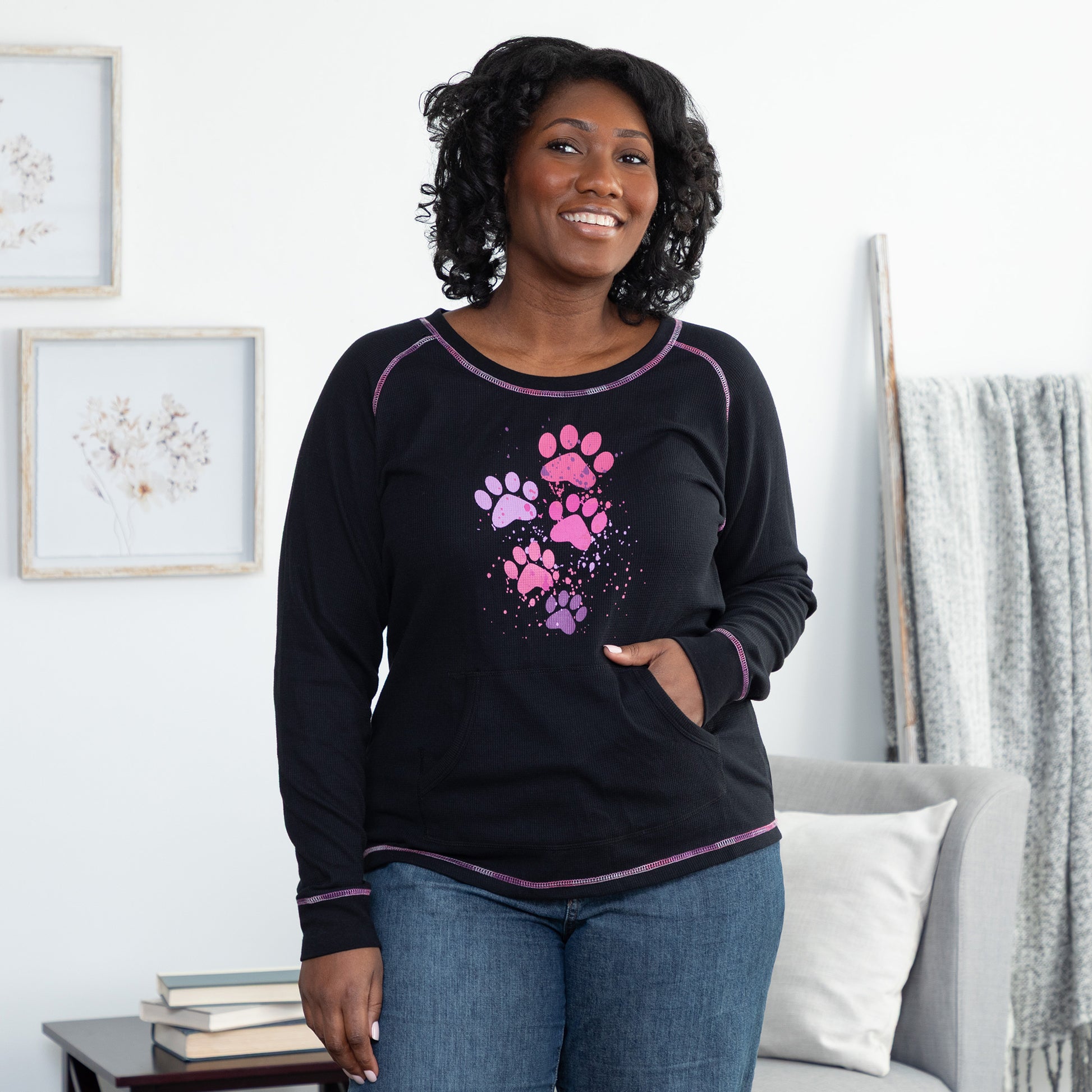 Woman wearing a black long-sleeve shirt with pink paw prints in a living room setting