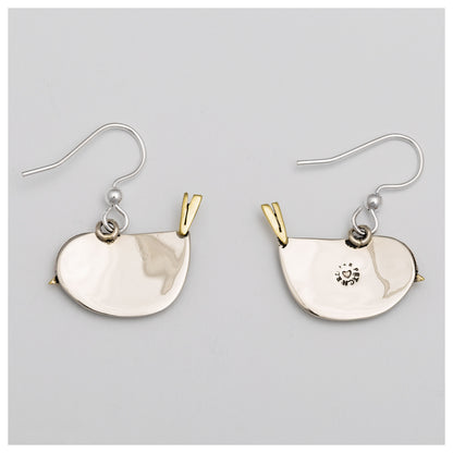 The silver and brass backs of bird shaped earrings, against a light gray background.