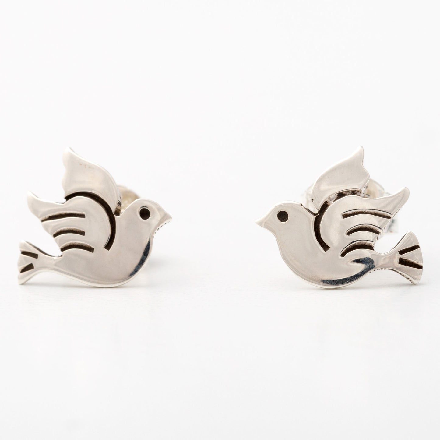 Pair of silver peace dove-shaped earrings on a white background