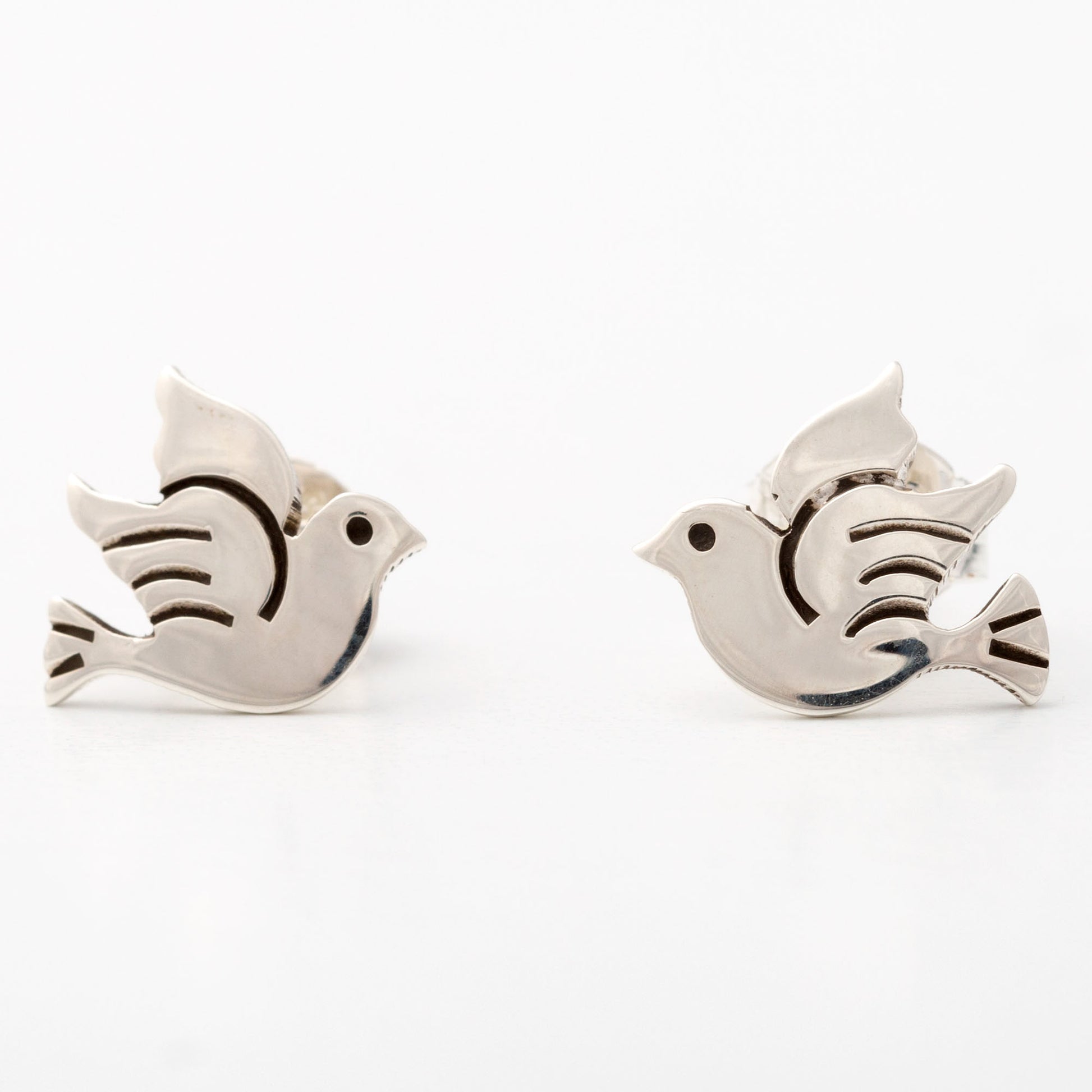 Pair of silver peace dove-shaped earrings on a white background