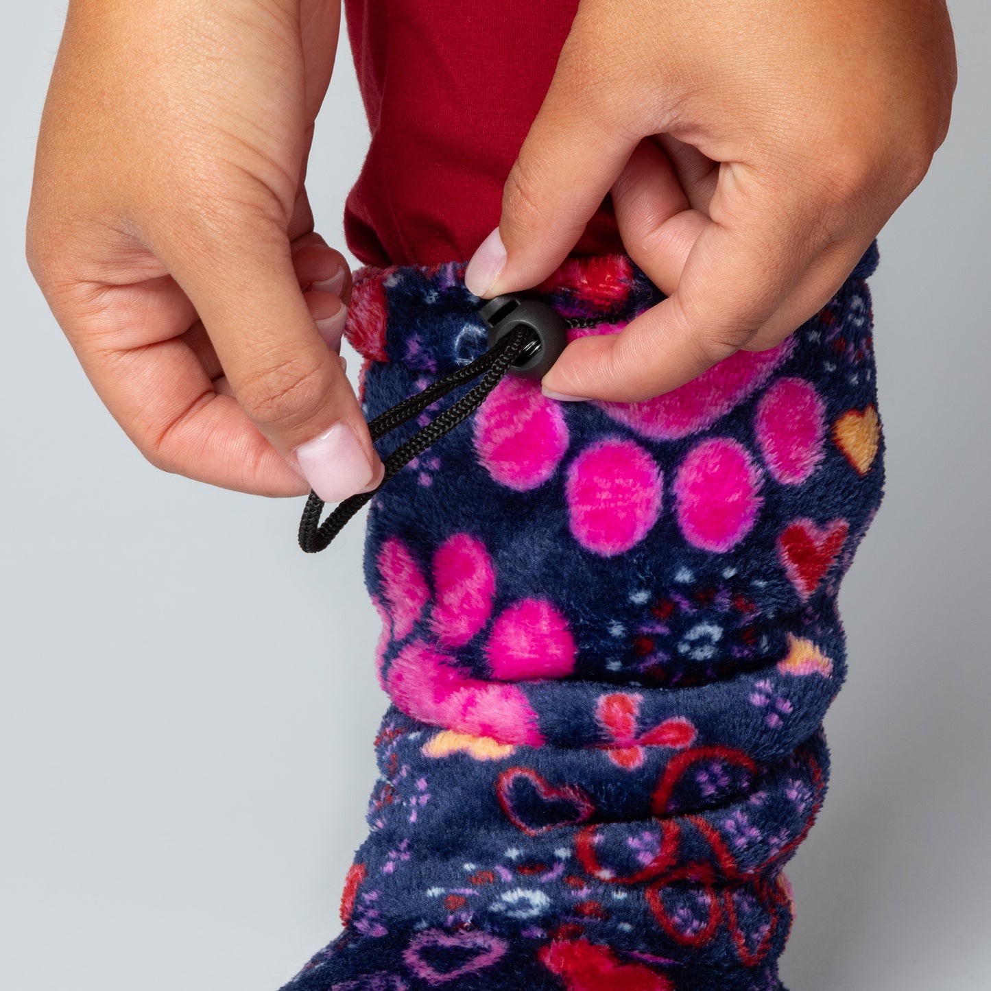Close-up of a colorful patterned fabric with a toggle being pulled, on a plain background.