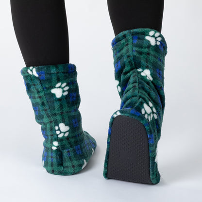 A pair of plush fleece slipper boots with a green and blue plaid pattern and white paw prints, shown on feet wearing black tights against a light gray background.