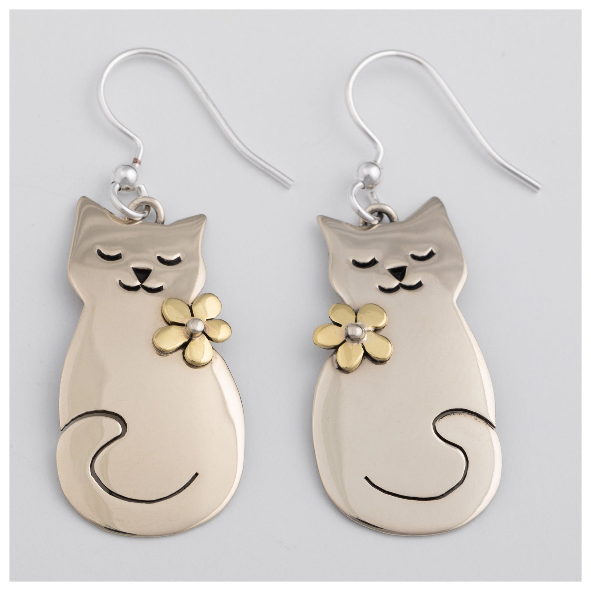 Cat-shaped earrings with floral details on a light gray background