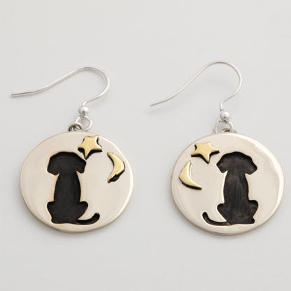 Silver earrings with black silhouette of a dog and gold star and moon on a white background