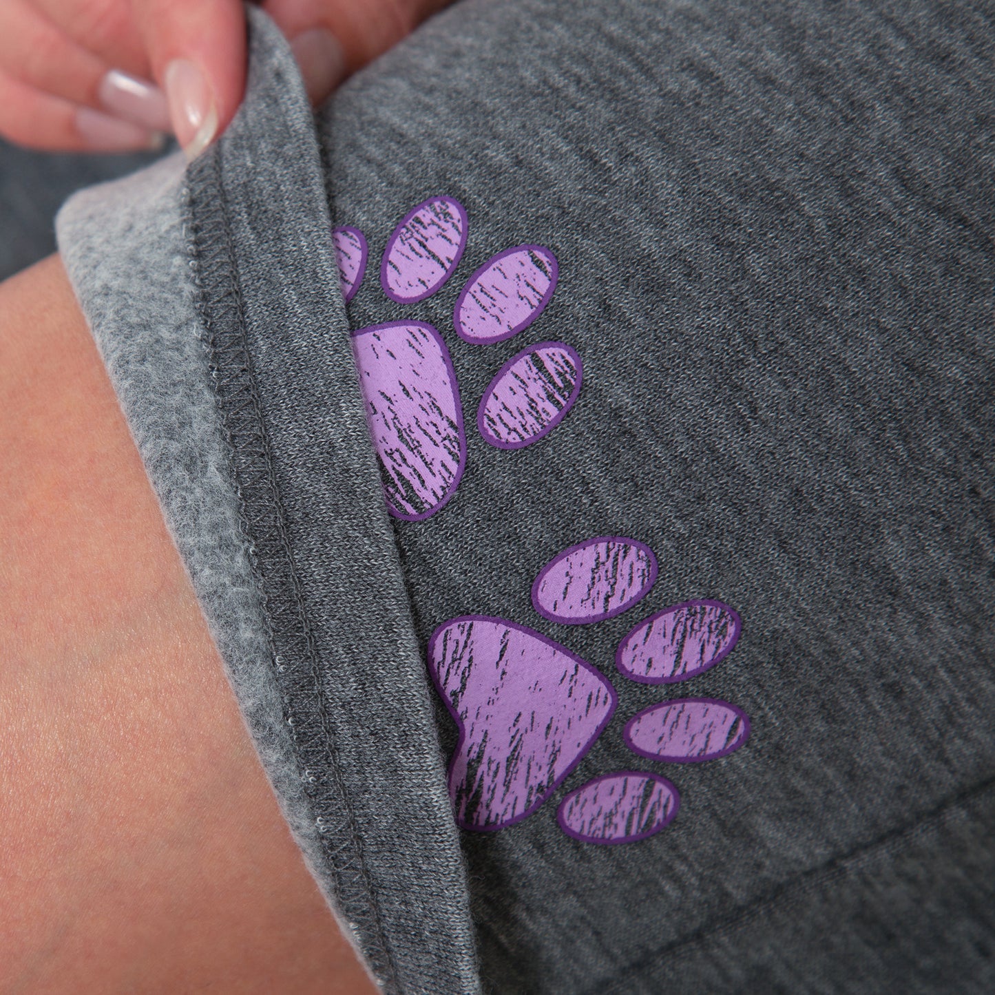 Gray fabric with purple paw prints held by a hand
