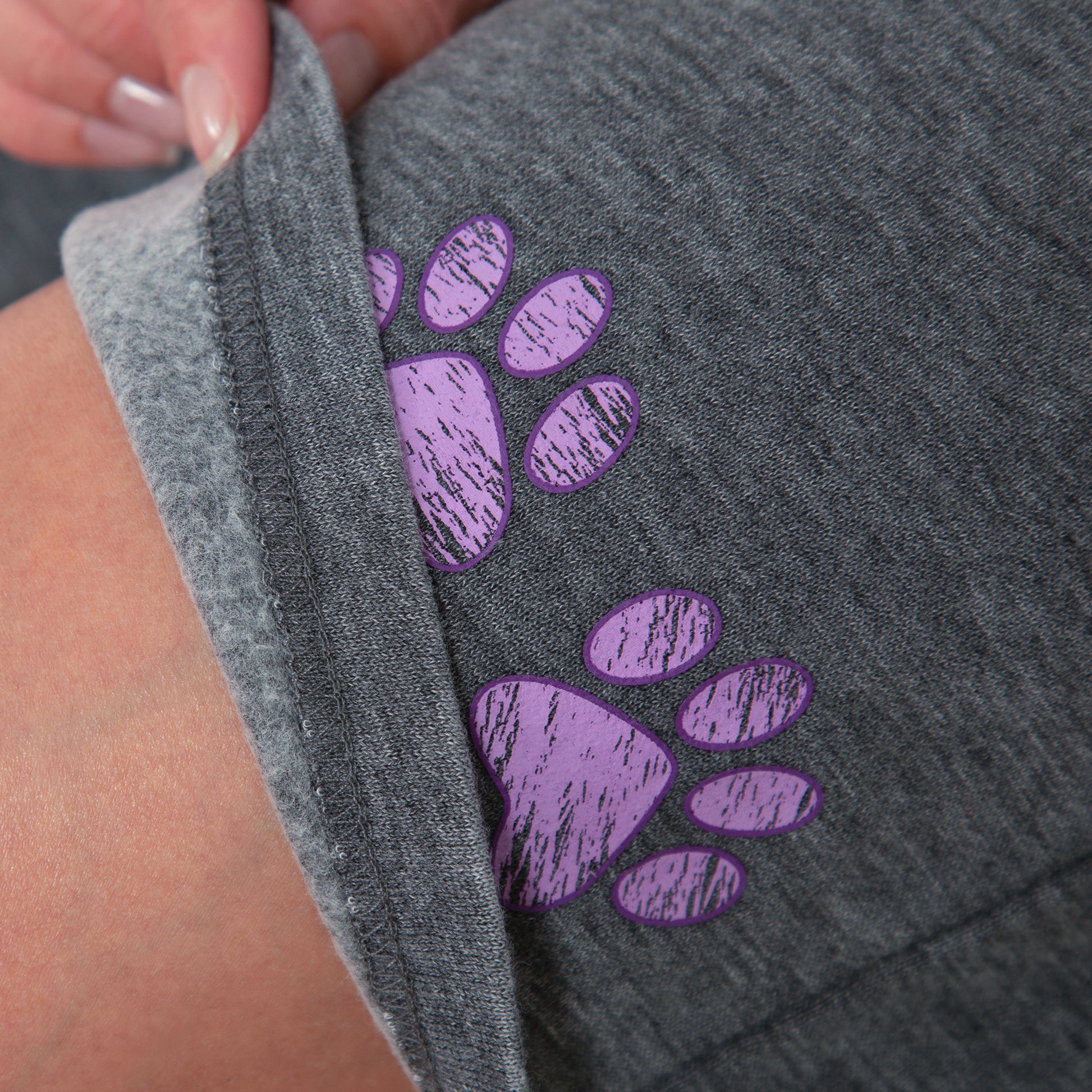 Gray fabric with purple paw prints held by a hand