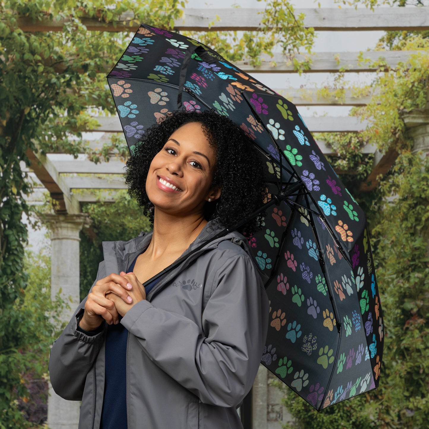 Woman holding a colorful paw print umbrella in an outdoor setting