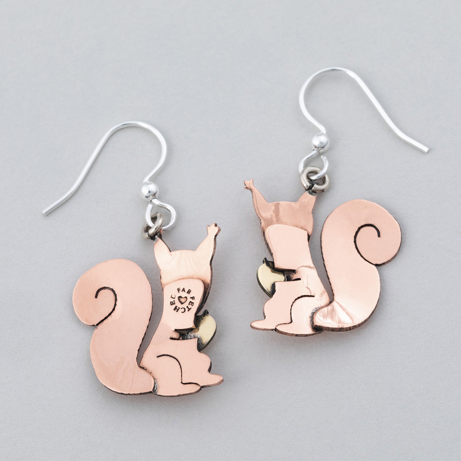 Backs of Squirrel-shaped copper earrings on a gray background.