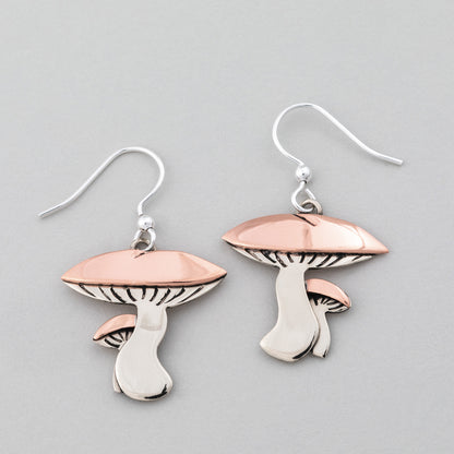 Mushroom-shaped earrings with copper and silver on a gray background.