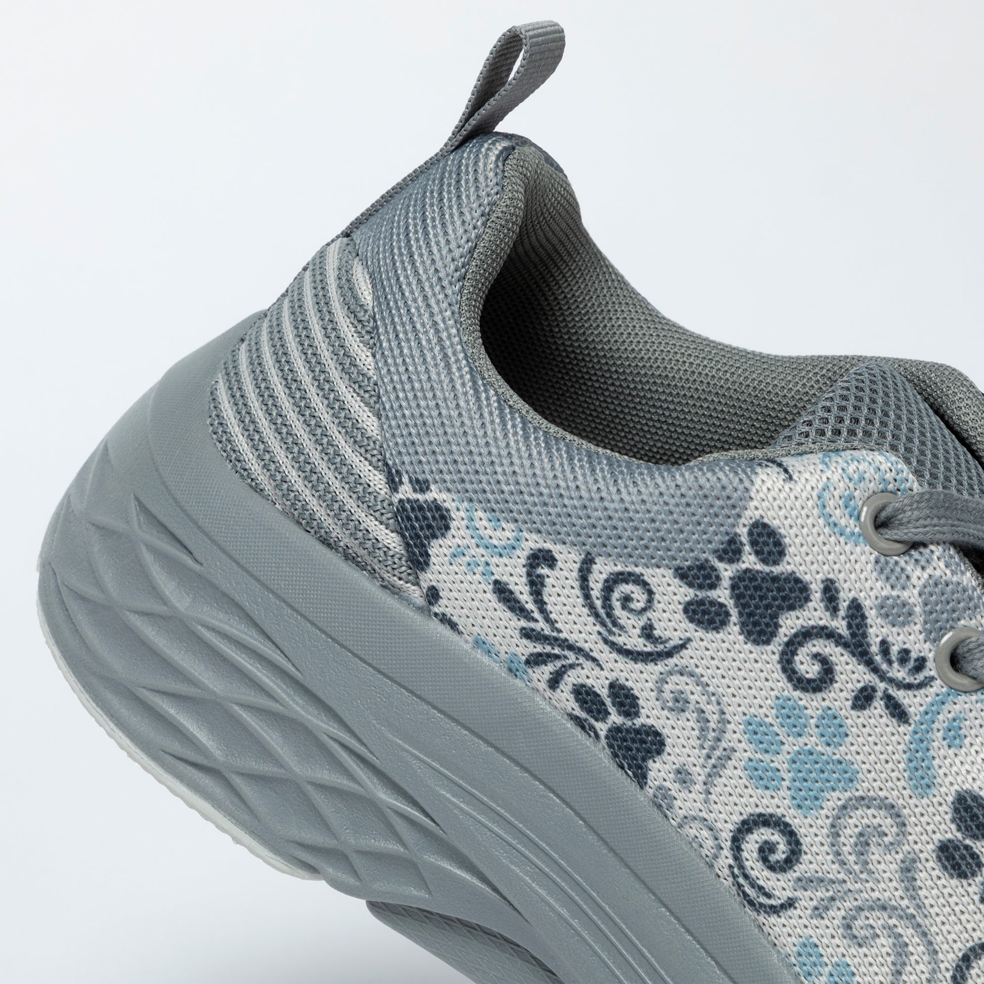 Gray sneaker with paw print pattern on a light gray background