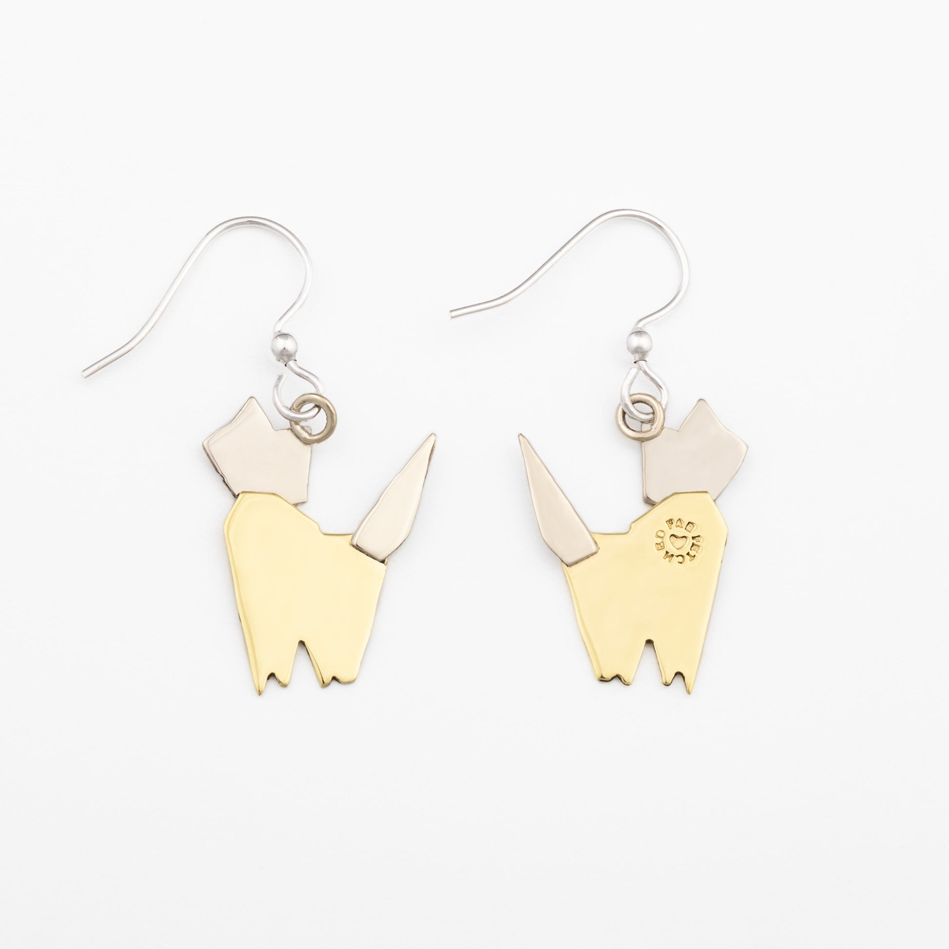 The backs of a pair of brass and silver cat -shaped earrings on a white background
