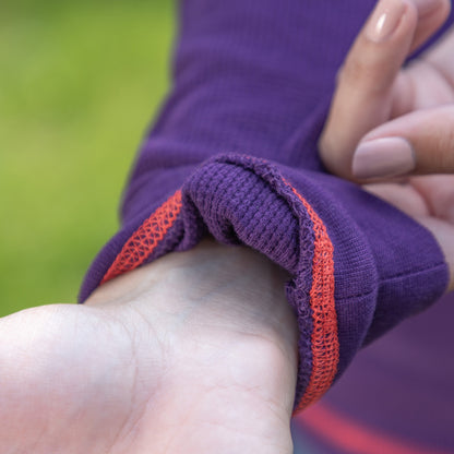 Close-up of pink contrast stitching on a purple thermal long sleeve top.
