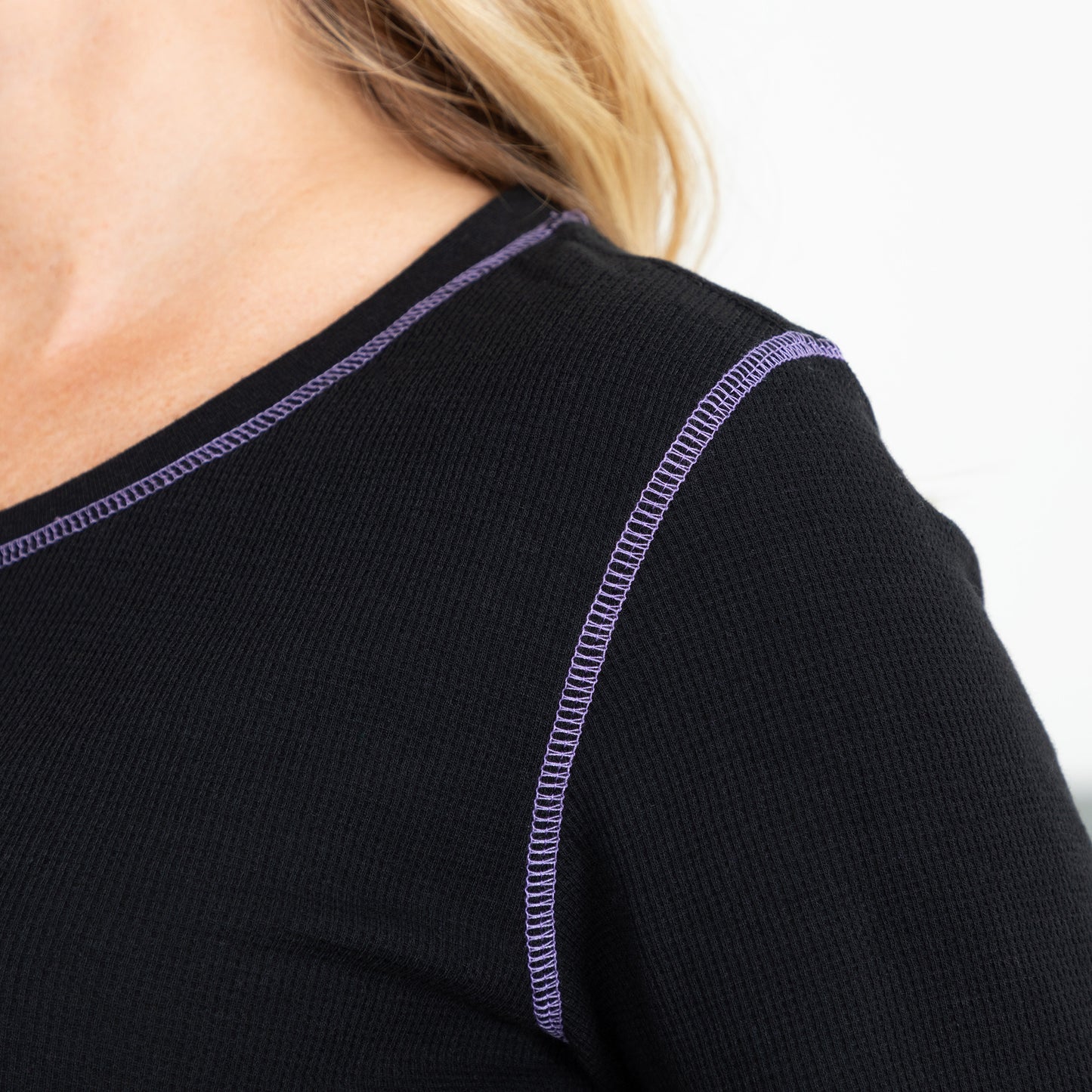 Close up of purple contrast stitching on a black thermal long sleeve tee.
