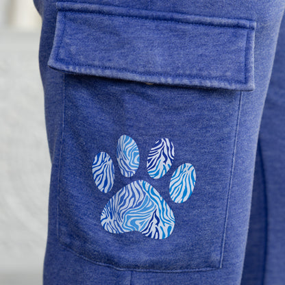 Close-up of a blue heather cargo pocket on pants with a paw print applique featuring blue and white zebra stripes.