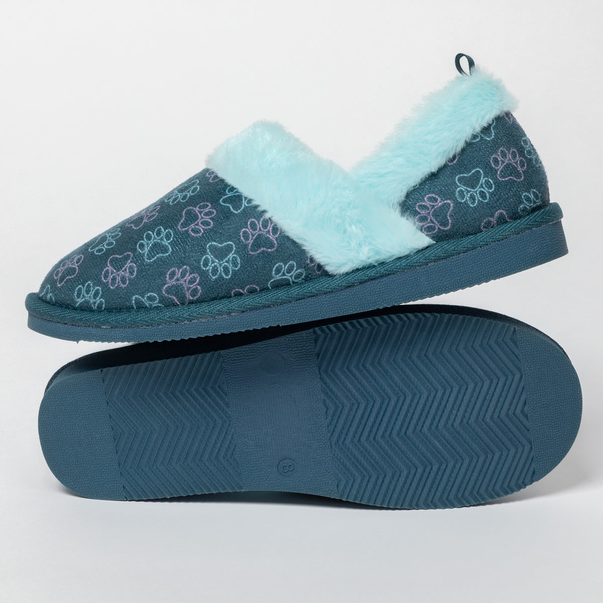 A pair of slip-on slippers shown on a clean white studio background, with one shoe standing upright to display the top and the other lying flat to show the sole. The upper is dark teal with an allover embroidered paw print pattern in light blue and lavender, and the interior is lined with fluffy pale aqua faux-fur trim.