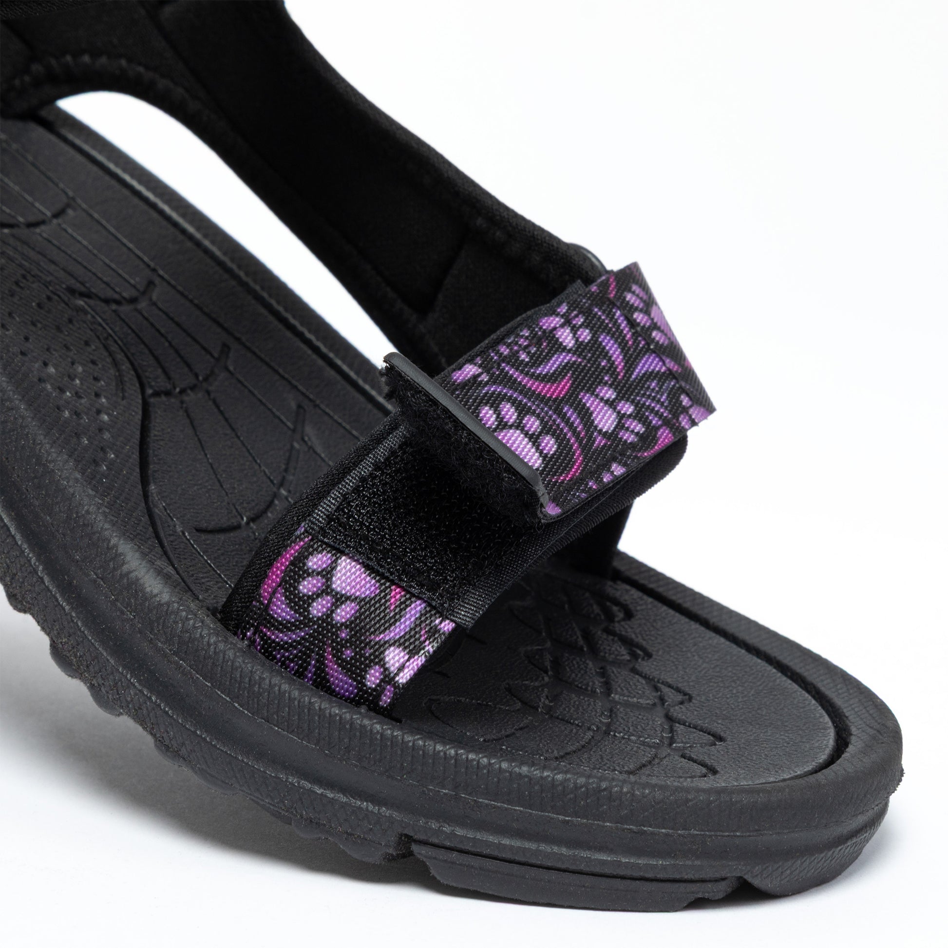 Black sandal with purple paw prints and swirls strap on a white background