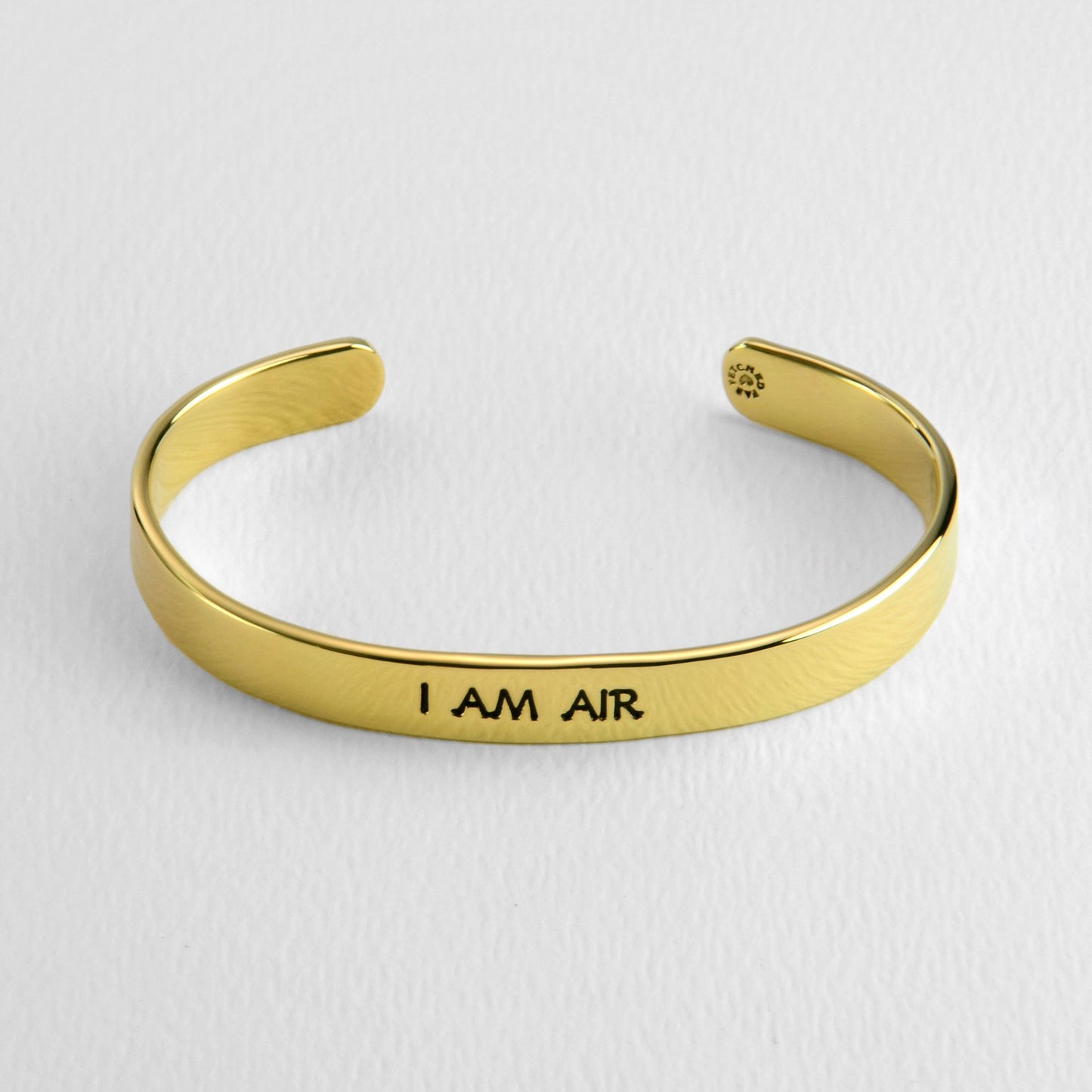 Brass bracelet with 'I AM AIR' engraving on a white background