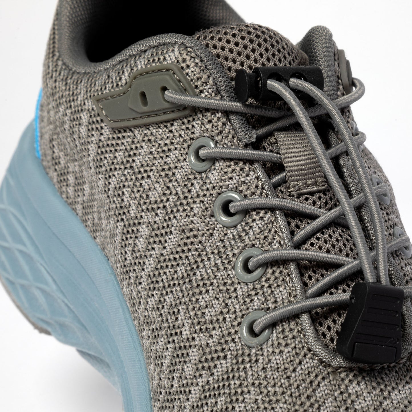 Close-up of a gray athletic shoe with bungee laces and a blue sole.