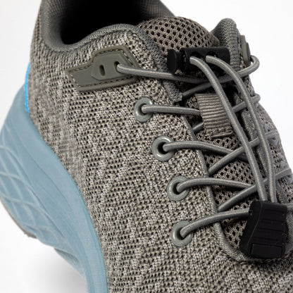 Close-up of a gray athletic shoe with bungee laces and a blue sole.