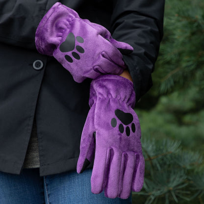 Purple gloves with paw prints held by a person against a blurred green background