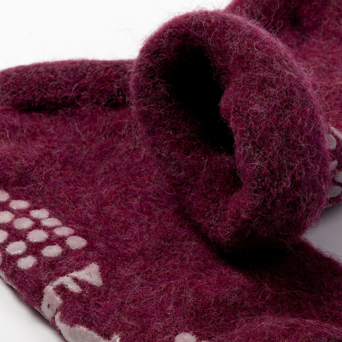 A close-up of a thick, fuzzy felted wool scarf in a deep burgundy color, featuring a white knit pattern along one edge and a rolled cuff showing the soft texture.