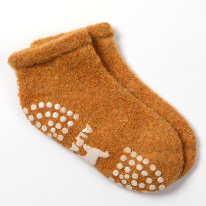 A pair of fuzzy, warm brown slip-on socks with white non-slip grip dots and a small white bear graphic on the sole, shown on a clean white background.