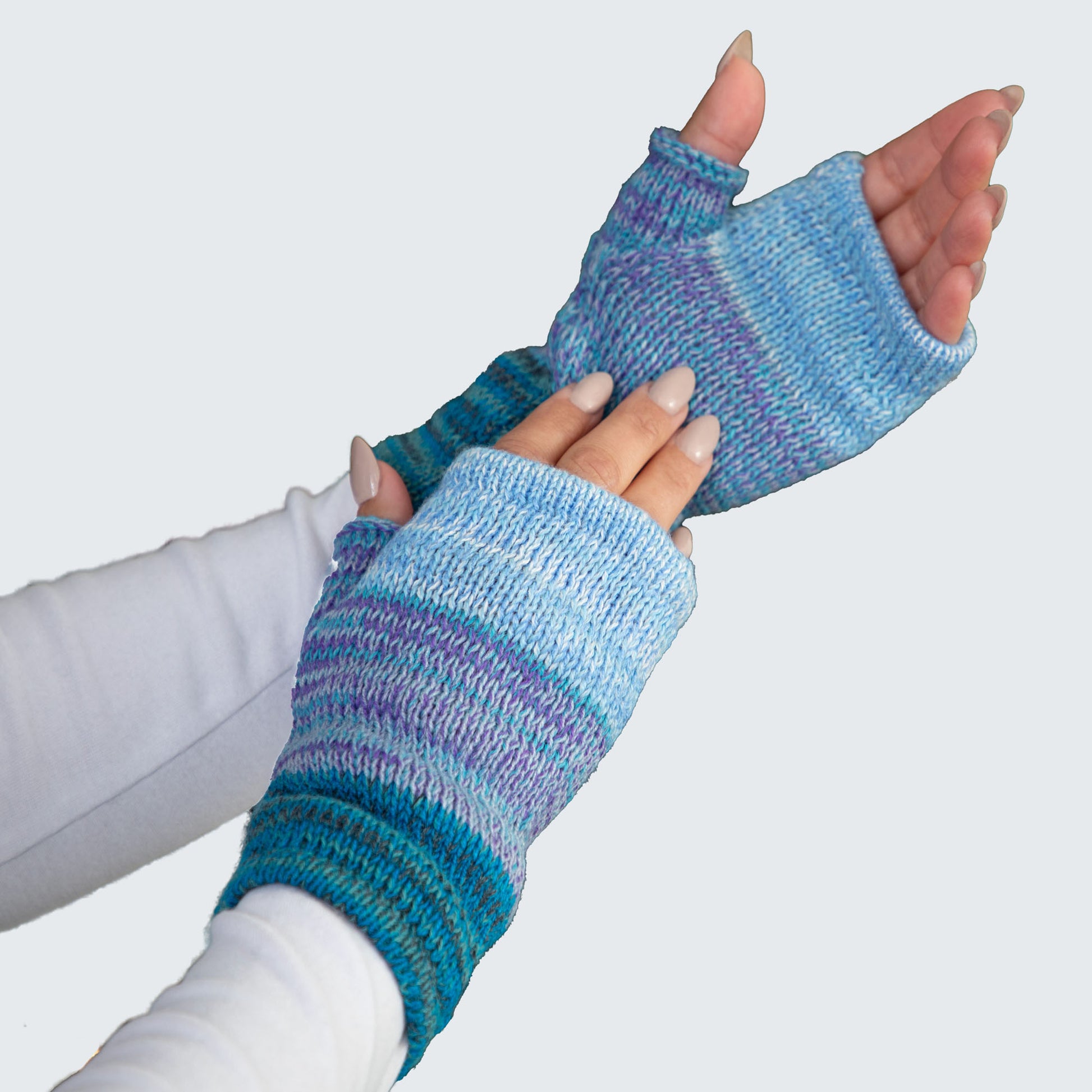 Blue and purple striped fingerless gloves worn by a person on a light gray background