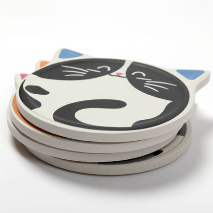 A stack of round coasters with a cartoon cat face design, featuring black and white cat patterns with blue and pink ear accents, on a clean white background.