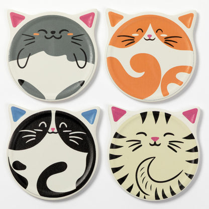 Four coasters featuring cartoon cat faces in different colorways: gray and white, orange and white, black and white, and cream and black with pink ears and nose. The coasters are arranged in a 2x2 grid on a plain white background.