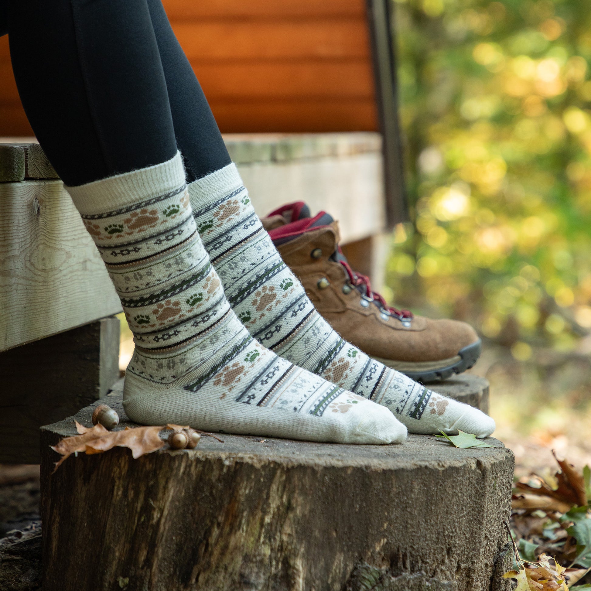 Person wearing patterned socks on a wooden stump with a blurred natural background