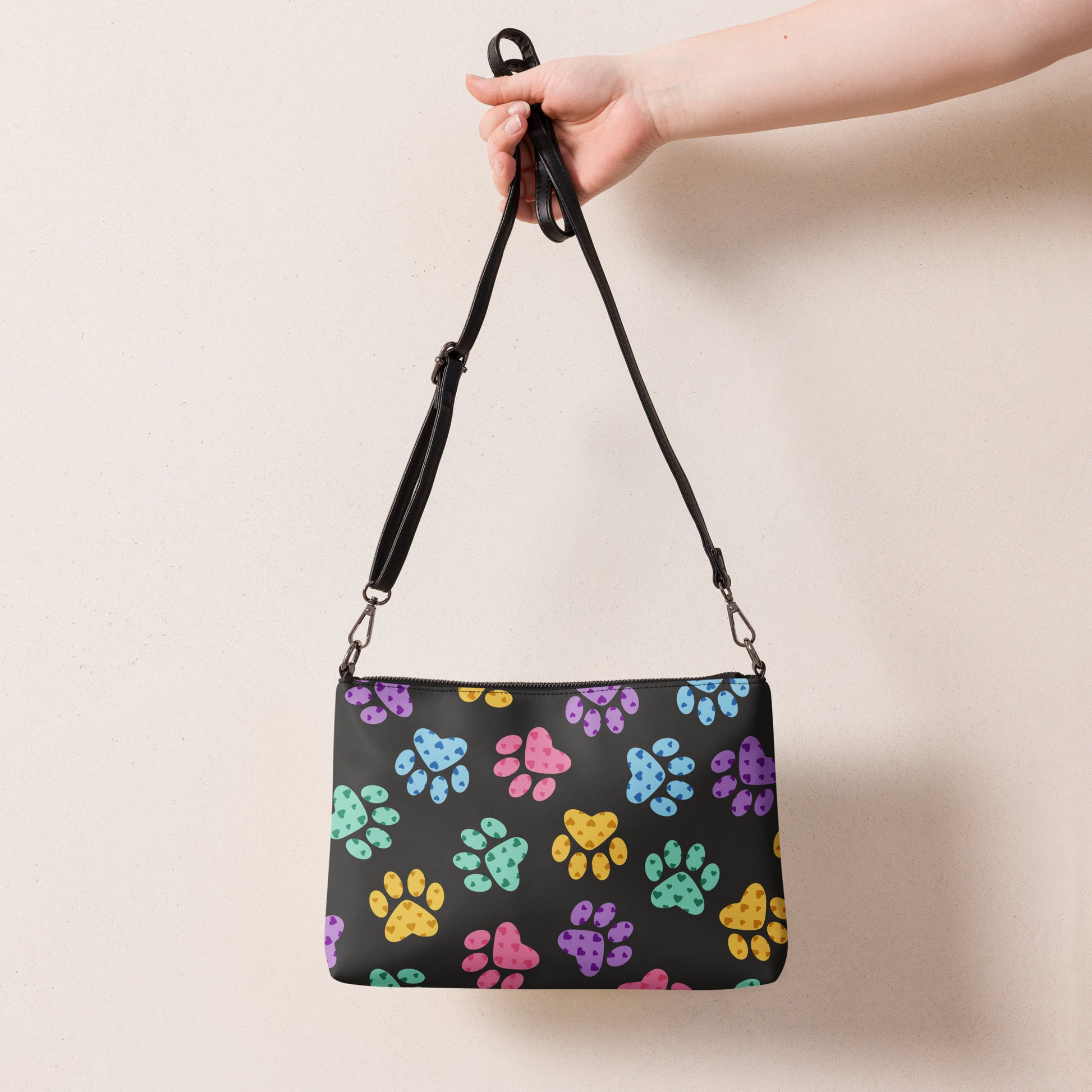Handbag with colorful paw prints held by a hand against a beige background