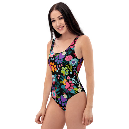 Side left view of Woman wearing one piece swimsuit with paw prints and leaves on it