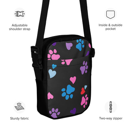 Black crossbody bag with colorful paw prints and heart designs, featuring text labels on a white background.