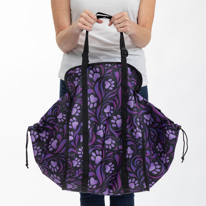 A person holding a large tote bag with a purple and black paw-print pattern, shown against a plain white background.