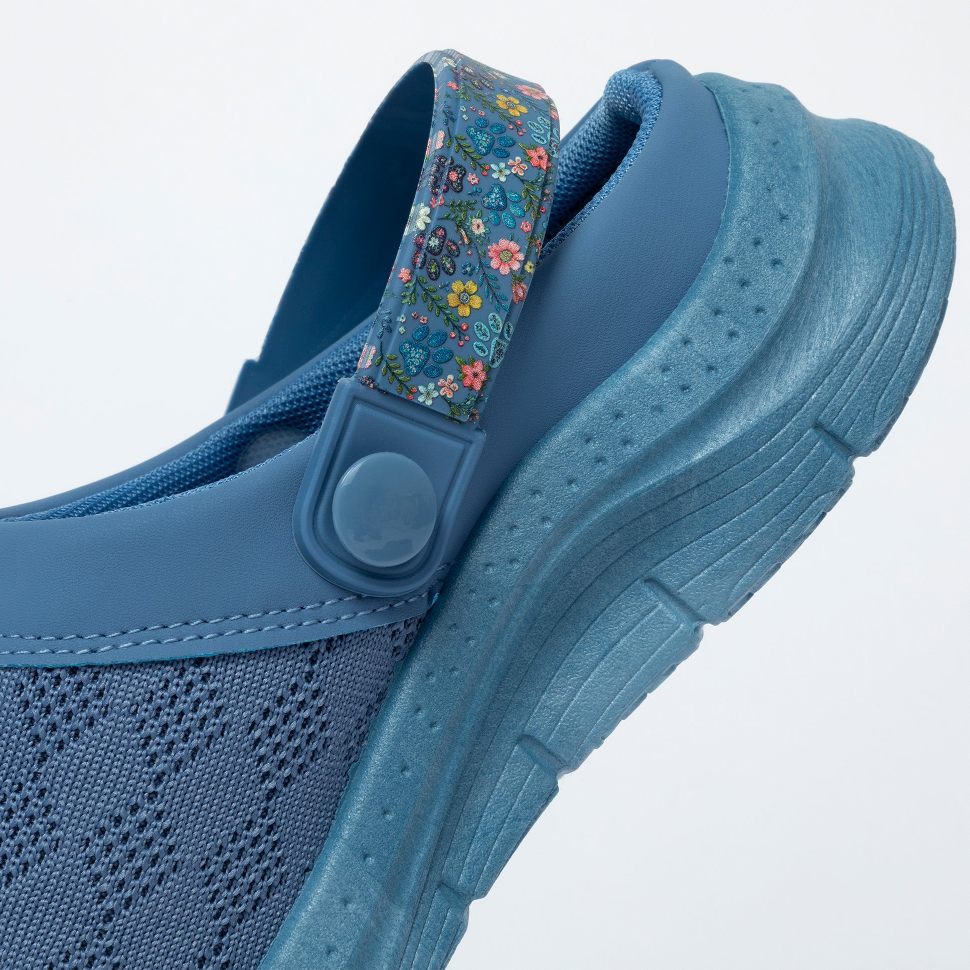 Blue clogs with floral strap on a light gray background