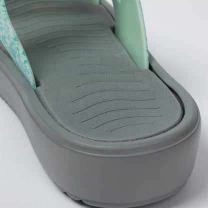 Close-up of a sandal with a textured sole on a light gray background