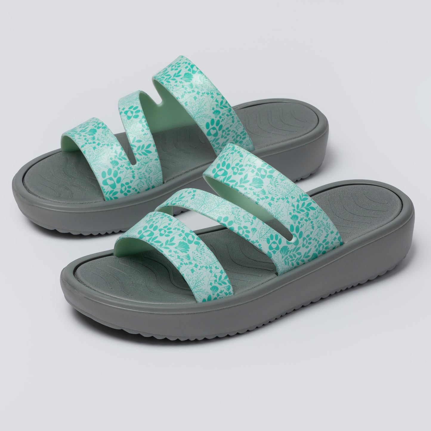 Pair of green sandals with floral pattern on a white background