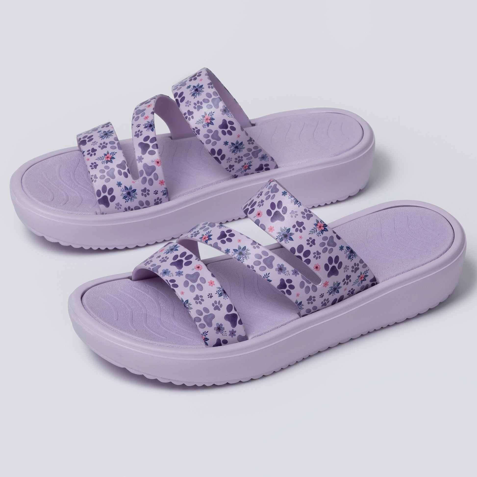 Pair of purple sandals with floral pattern on a light gray background