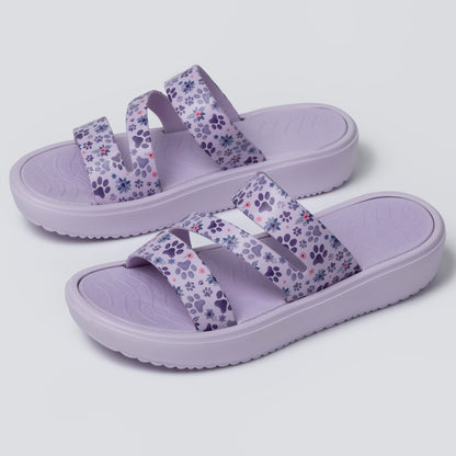 Pair of purple sandals with floral pattern on a light gray background