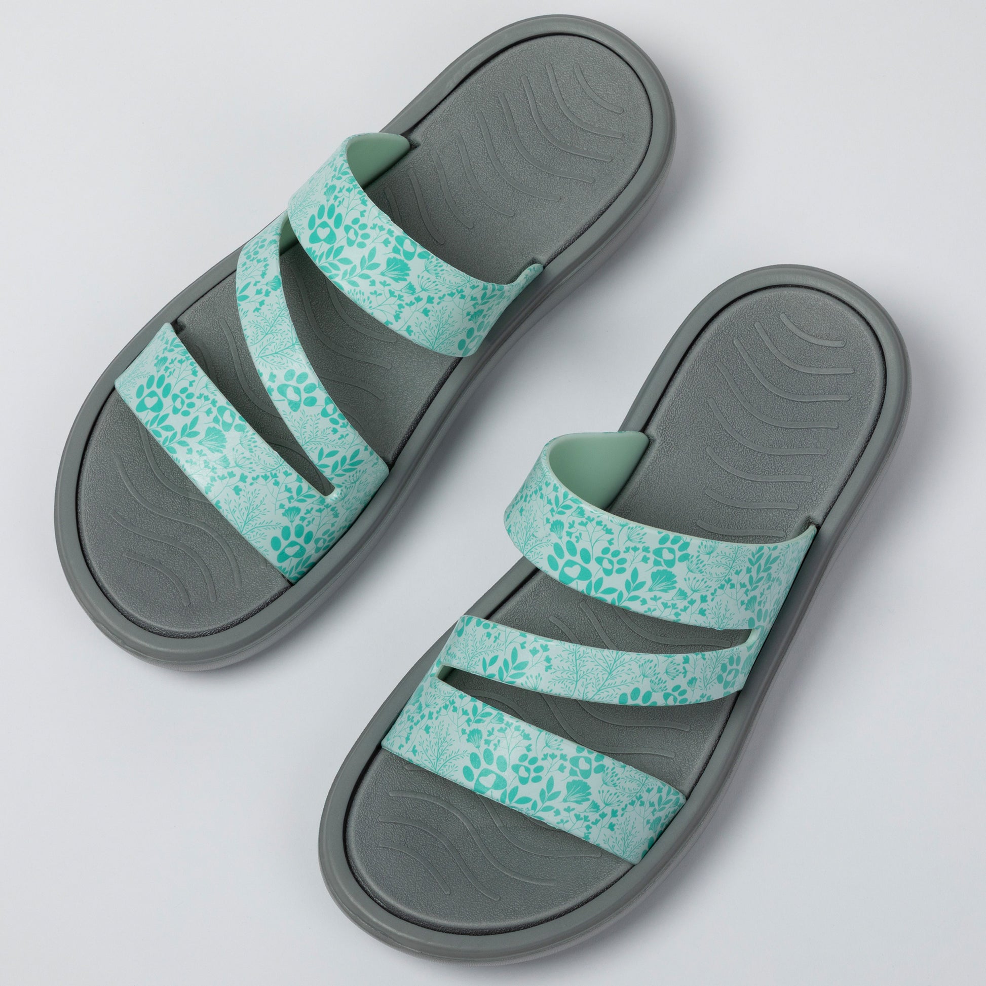 Pair of gray sandals with floral patterned straps on a light gray background