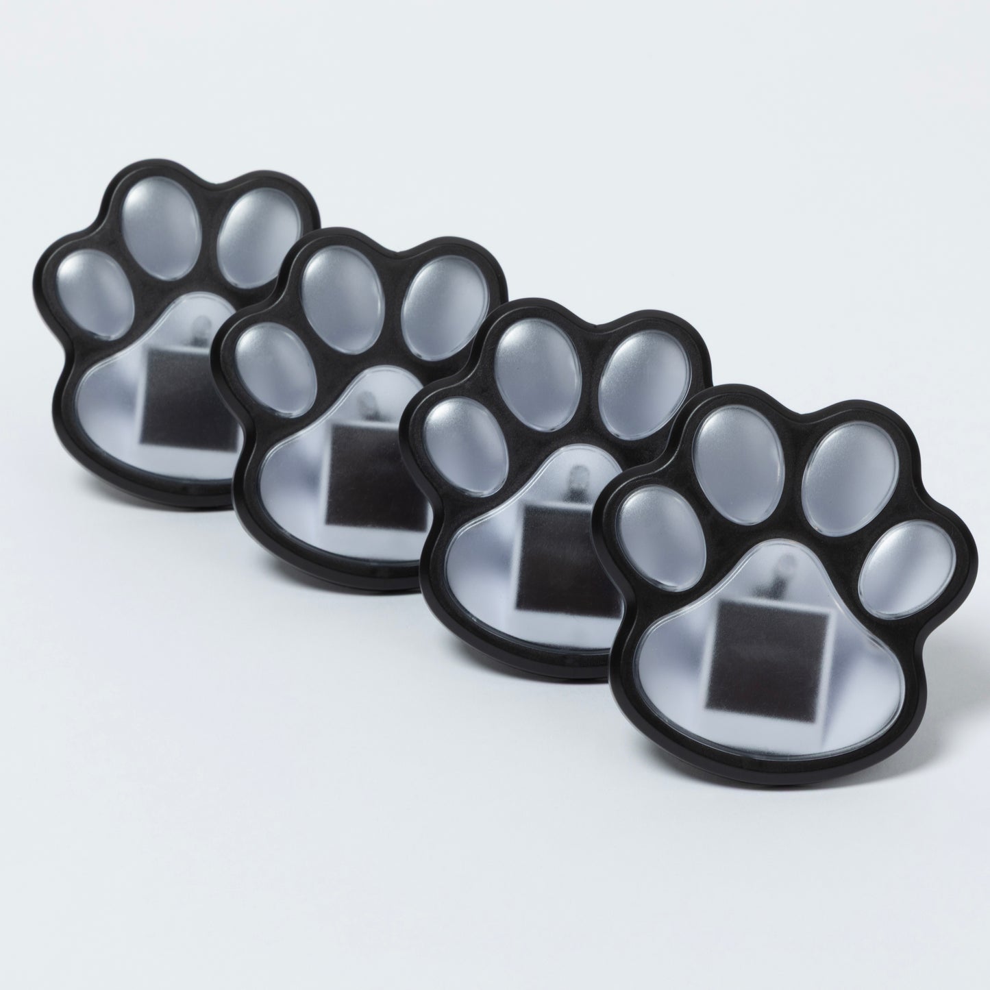 Four paw-shaped black and clear containers on a light gray background