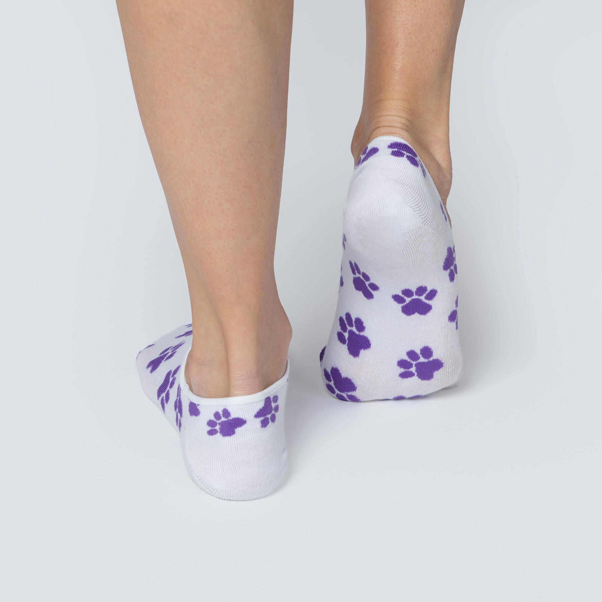 White socks with purple paw prints worn by a person on a light gray background
