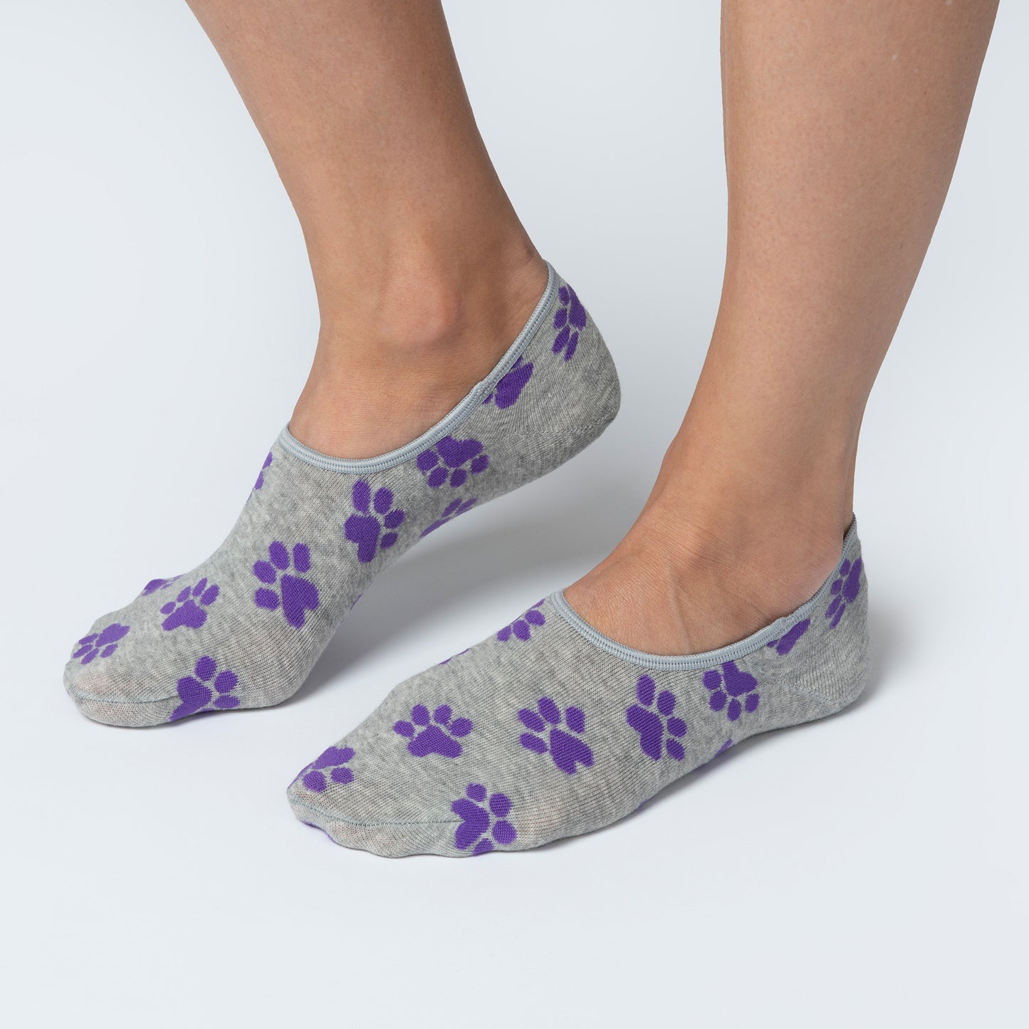 Gray socks with purple paw prints worn by a person on a white background
