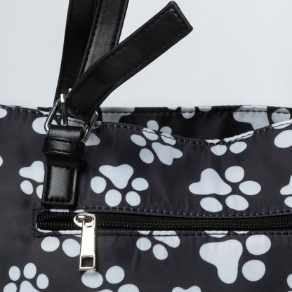 Black bag with white paw prints and a black strap on a light gray background
