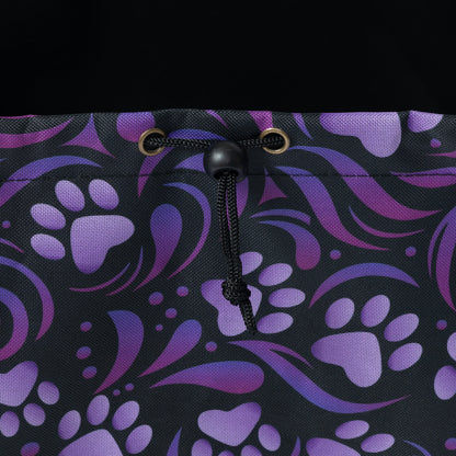Close-up of a black drawstring bag featuring a purple and violet paw print and swirl pattern, with a black drawstring and gold eyelets.